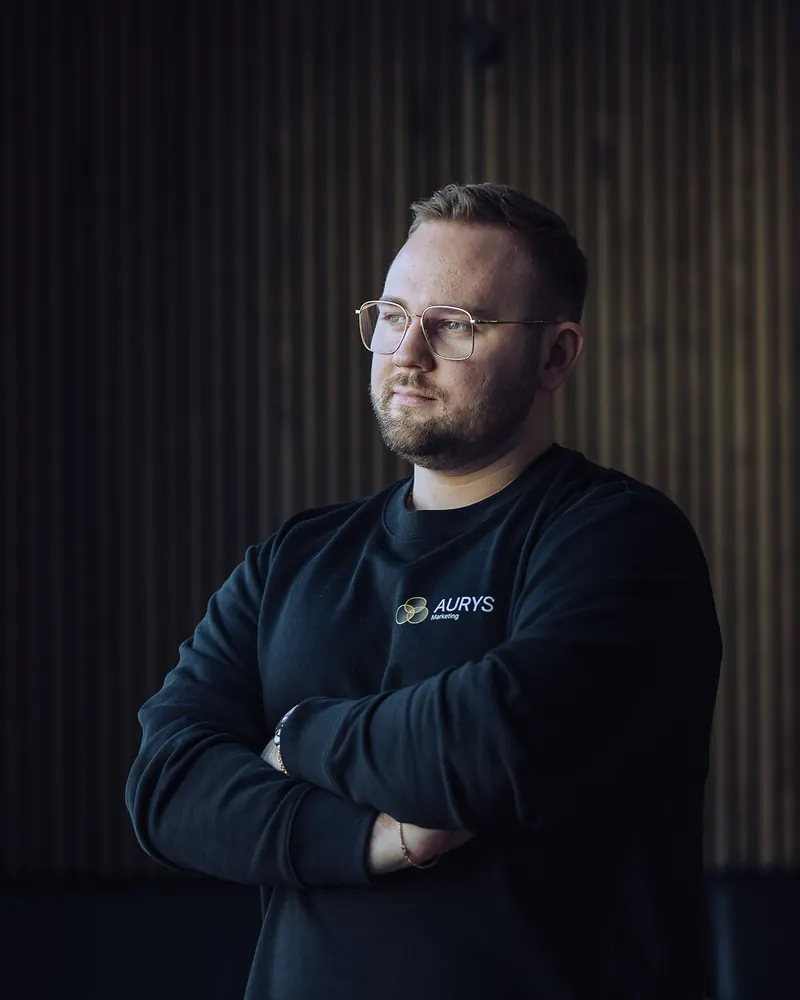Tim G. B. Wöhler vor der dunklen Holzwand