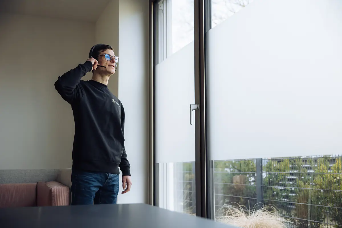 AURYS-Mitarbeiter mit Headset am Fenster